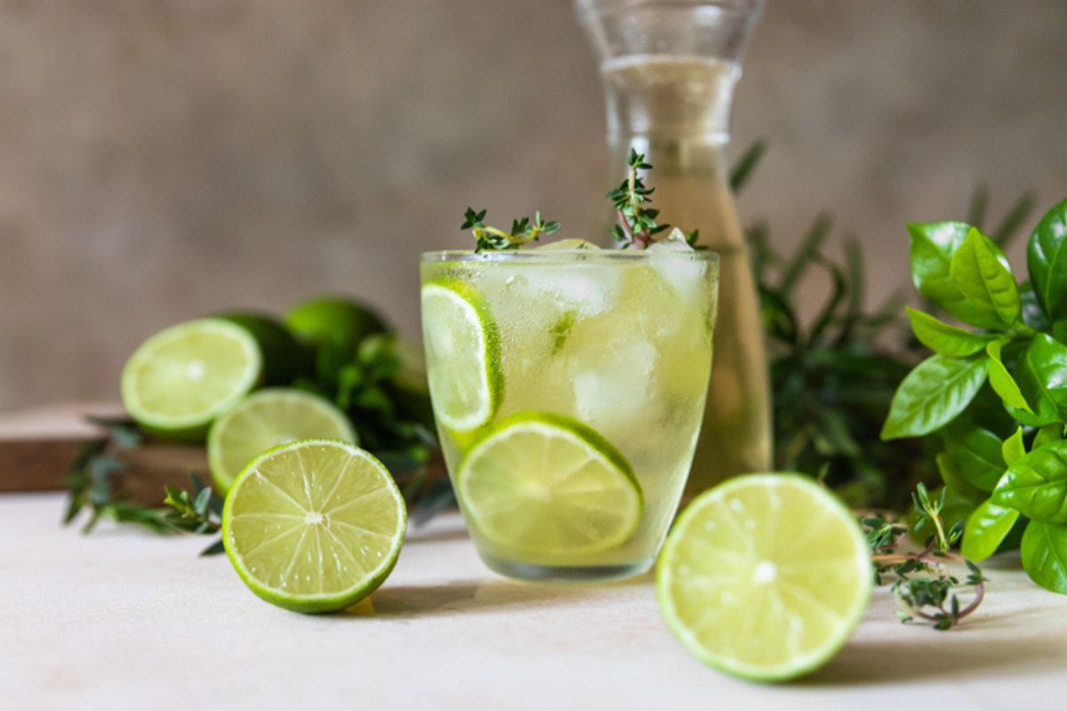 Imagem colorida de suco de limão com limões ao redor do copo