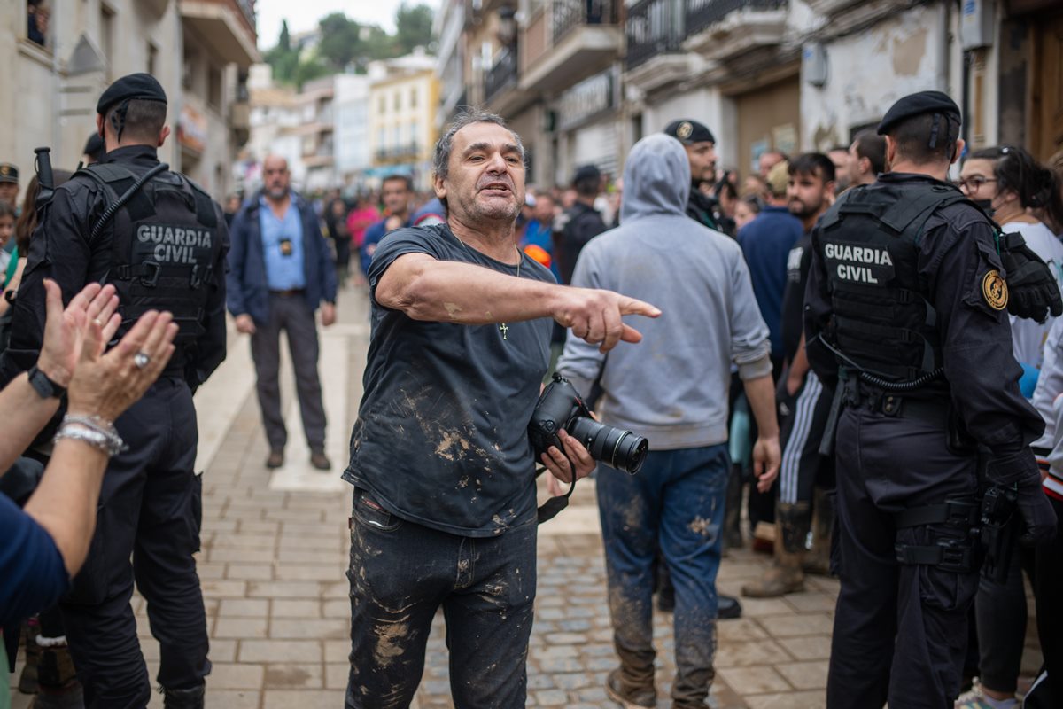 Foto colorida de homem com câmera na mão e com a postura de que está brigando - Metrópoles