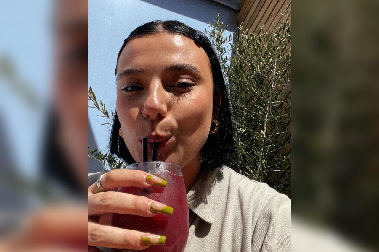 Foto selfie da jovem Saskia Clark tomando uma bebida. Metrópoles