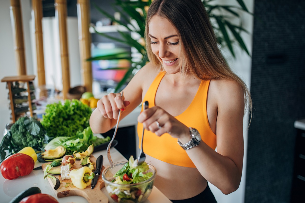 mulher em forma fazendo salada de vegetais saudável para o café da manhã na cozinha. Conceito de vida saudável. Metrópoles