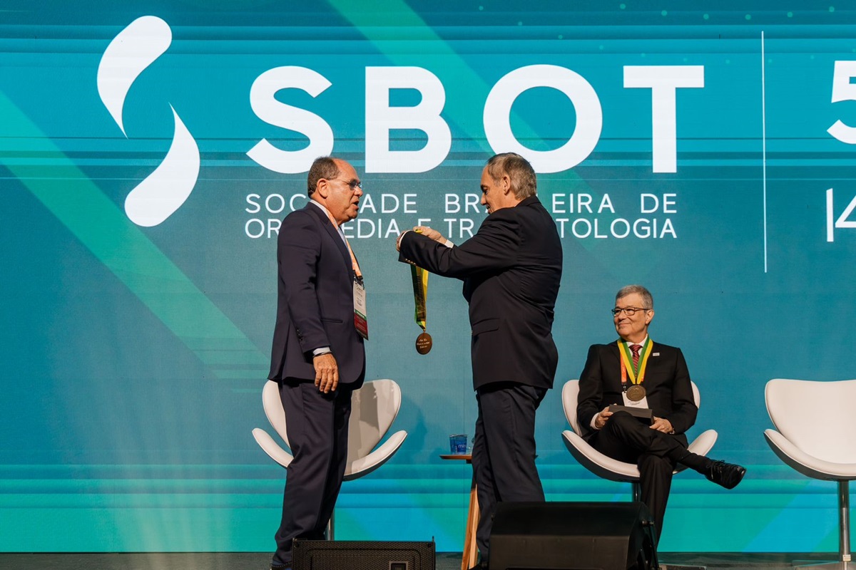 Foto colorida de homem recebendo medalha - Metrópoles