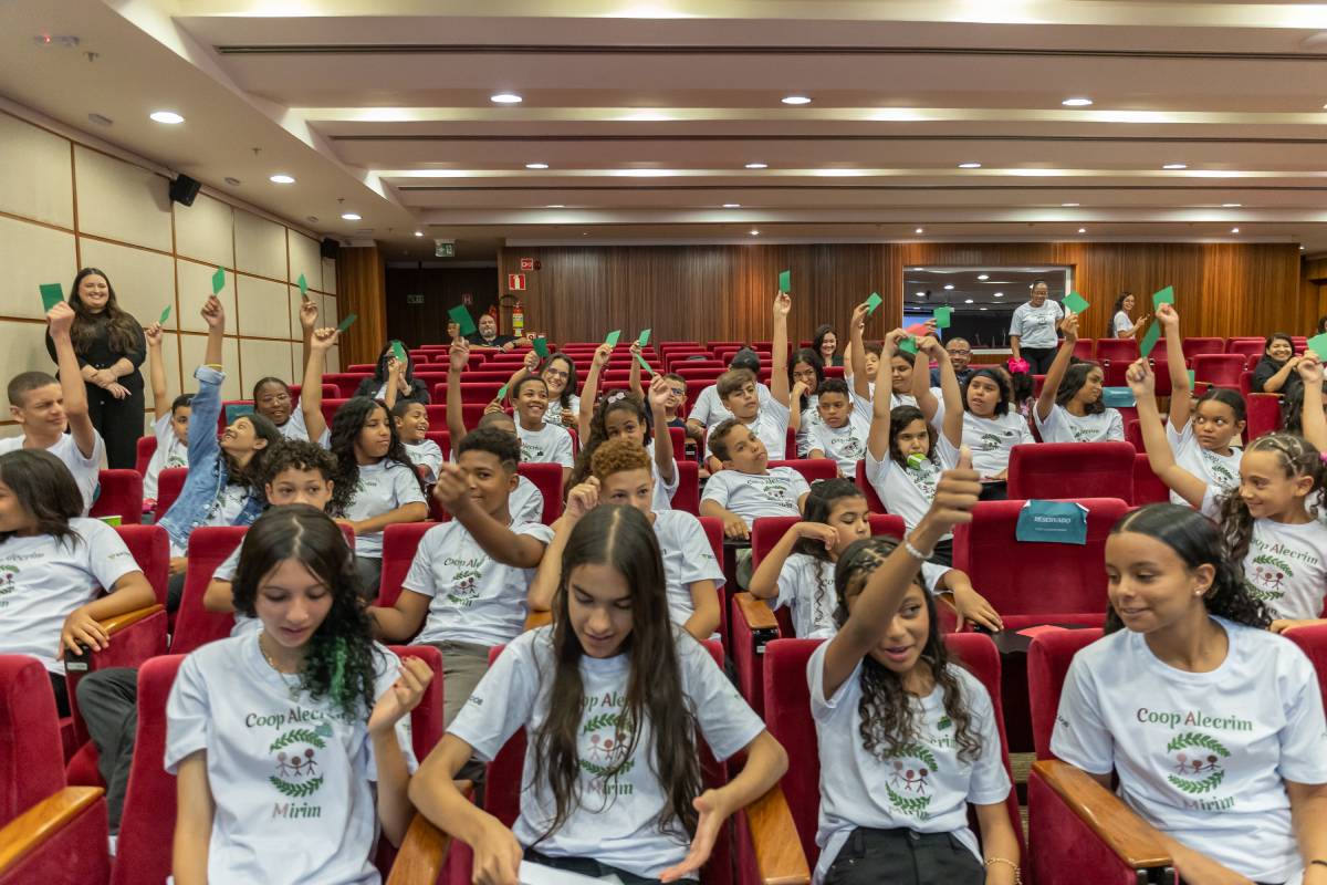 Fotografia colorida mostrando estudantes em auditório mostrando cartões verdes-Metrópoles