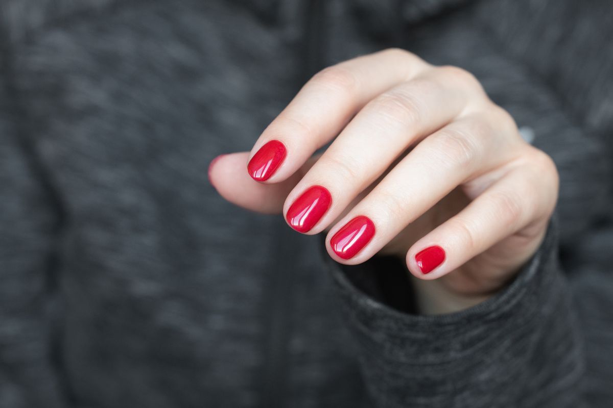 Foto colorida de mulheres com unhas vermelho - Metrópoles