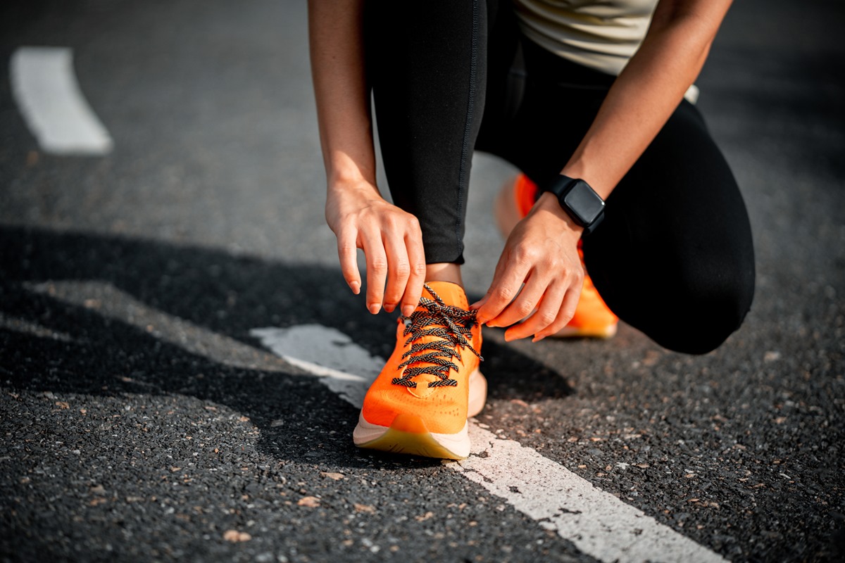 Tênis de corrida. Mulher amarrando cadarços de sapato. Closeup de corredora de fitness esportivo feminino se preparando para correr. Metrópoles