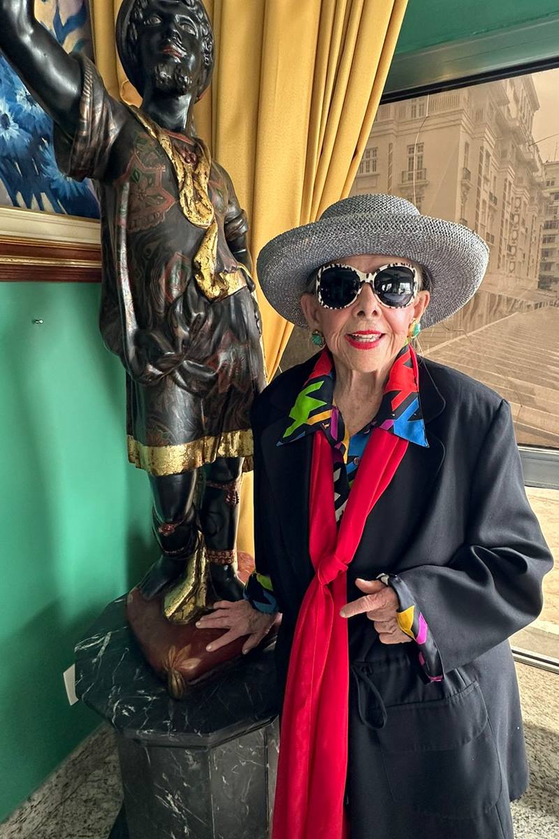 Foto colorida de mulher com chapéu, óculos-escuros e terno - Metrópoles