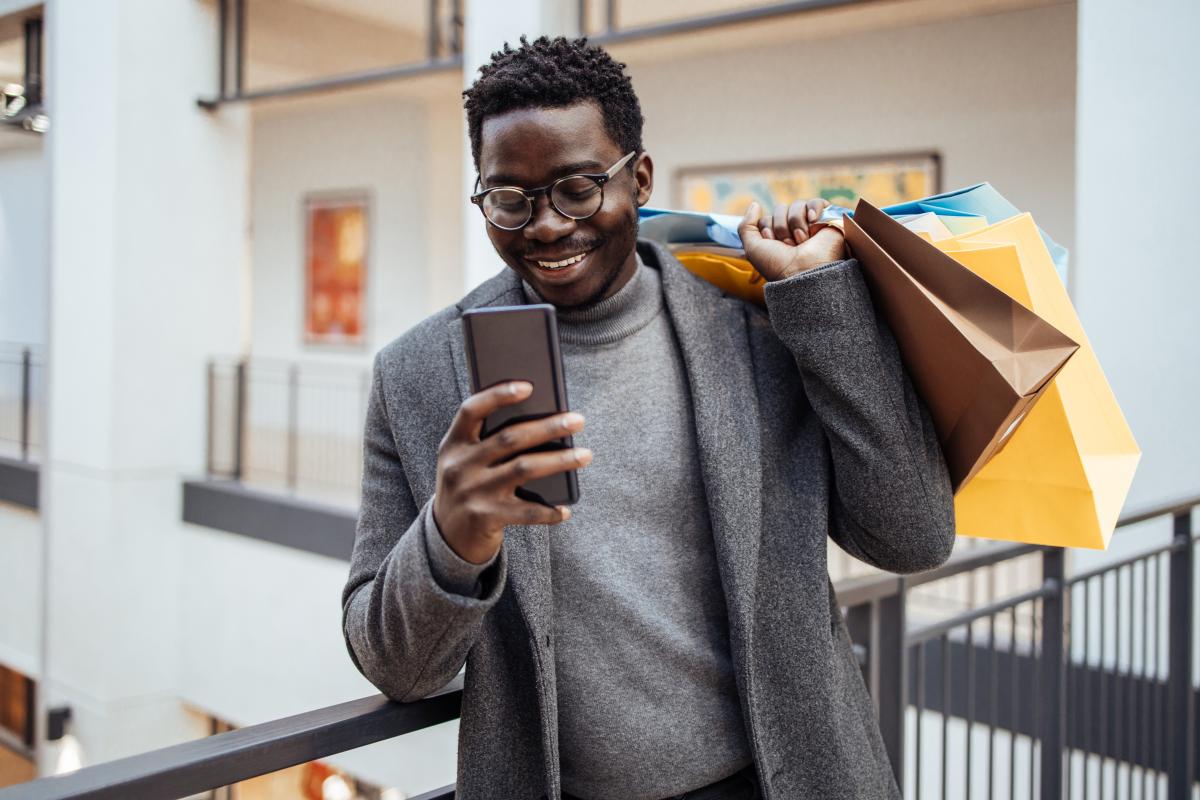 Na imagem com cor, uma homem com compras de black friday - metrópoles