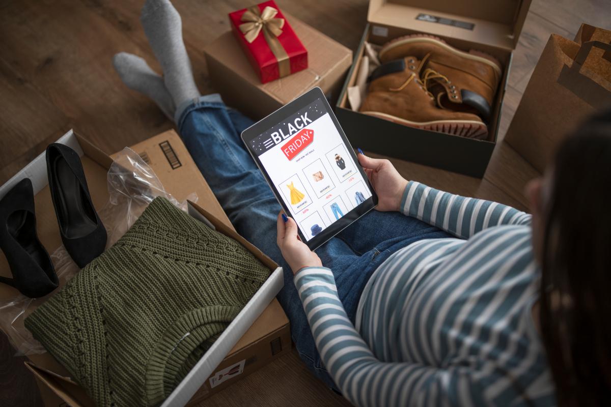 Na imagem com cor, uma mulher com compras de black friday - metrópoles