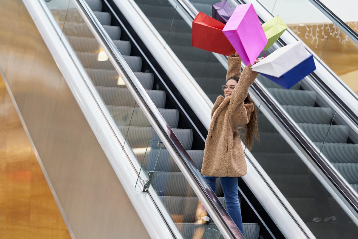 Na imagem com cor, uma mulher com compras de black friday - metrópoles