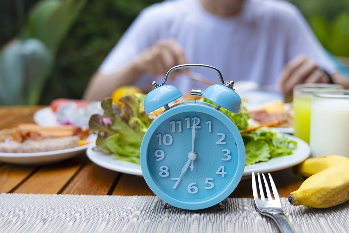 Foto colorida de prato de salada e relógio azul - Metrópoles