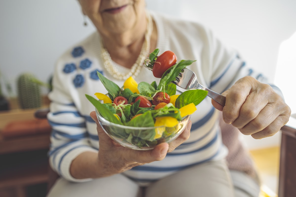 Foto colorida de mulher segurando prato de salada - Metrópoles