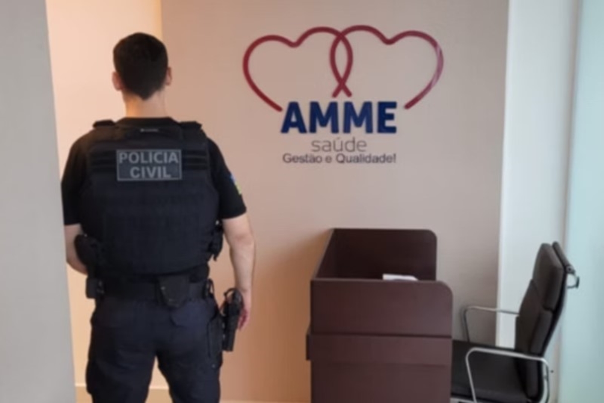 Foto colorida de policial diante de emblema da empresa Amme Saúde - Metrópoles