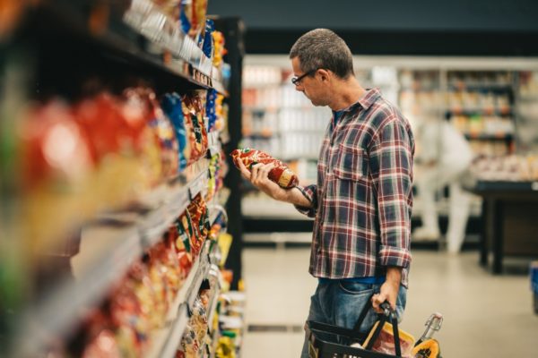 Imagem colorida, um homem avaliando um produto dentro de um mercado - Metrópoles