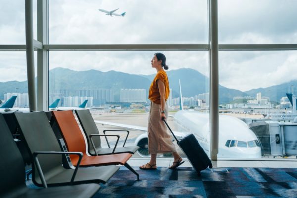 Imagem colorida, uma mulher no aeroporto carregando a mala de viagem - Metrópoles