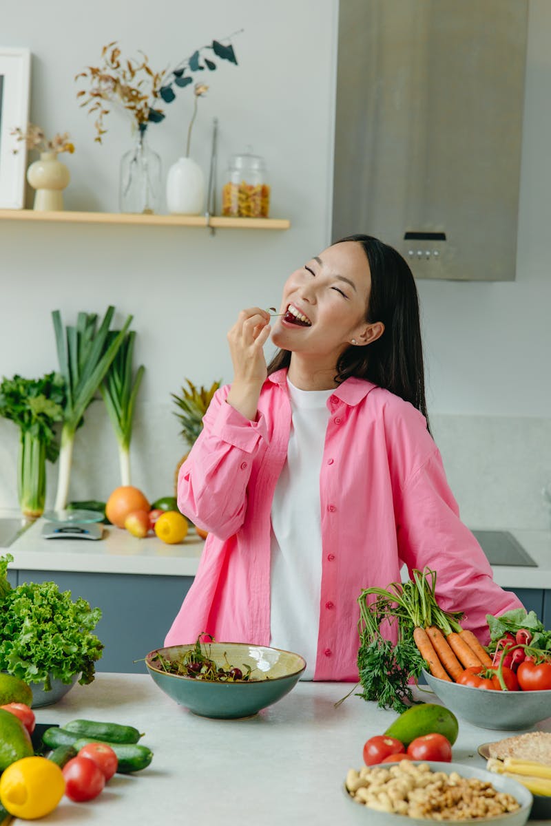 Jovem mulher asiática se alimentando em cozinha - Metrópoles