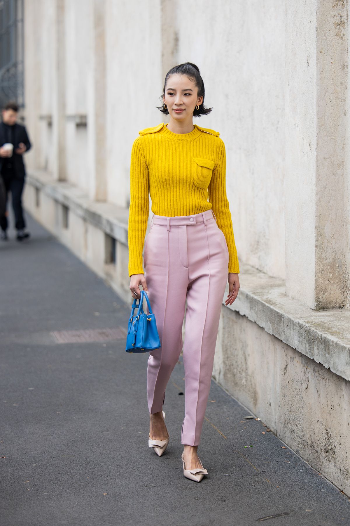 Look de street style com suéter amarelo, calça rosa-claro e bolsa azul - Metrópoles