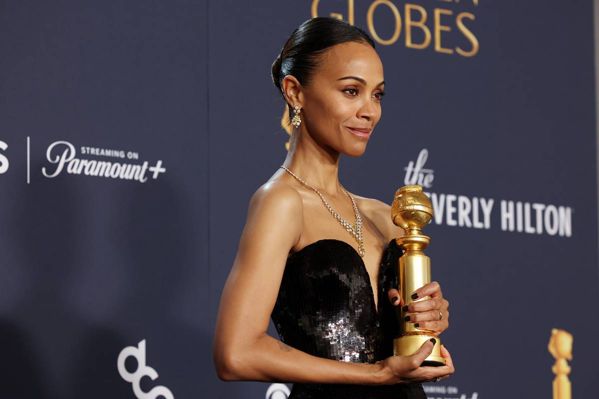 Imagem colorida de Zoe Saldana no Globo de Ouro, segurando estatueta - Metrópoles