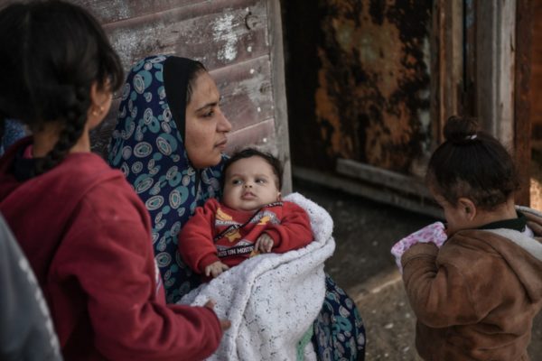 Imagem colorida, mulher segurando um bebê no colo, acompanhada de duas crianças - Metrópoles