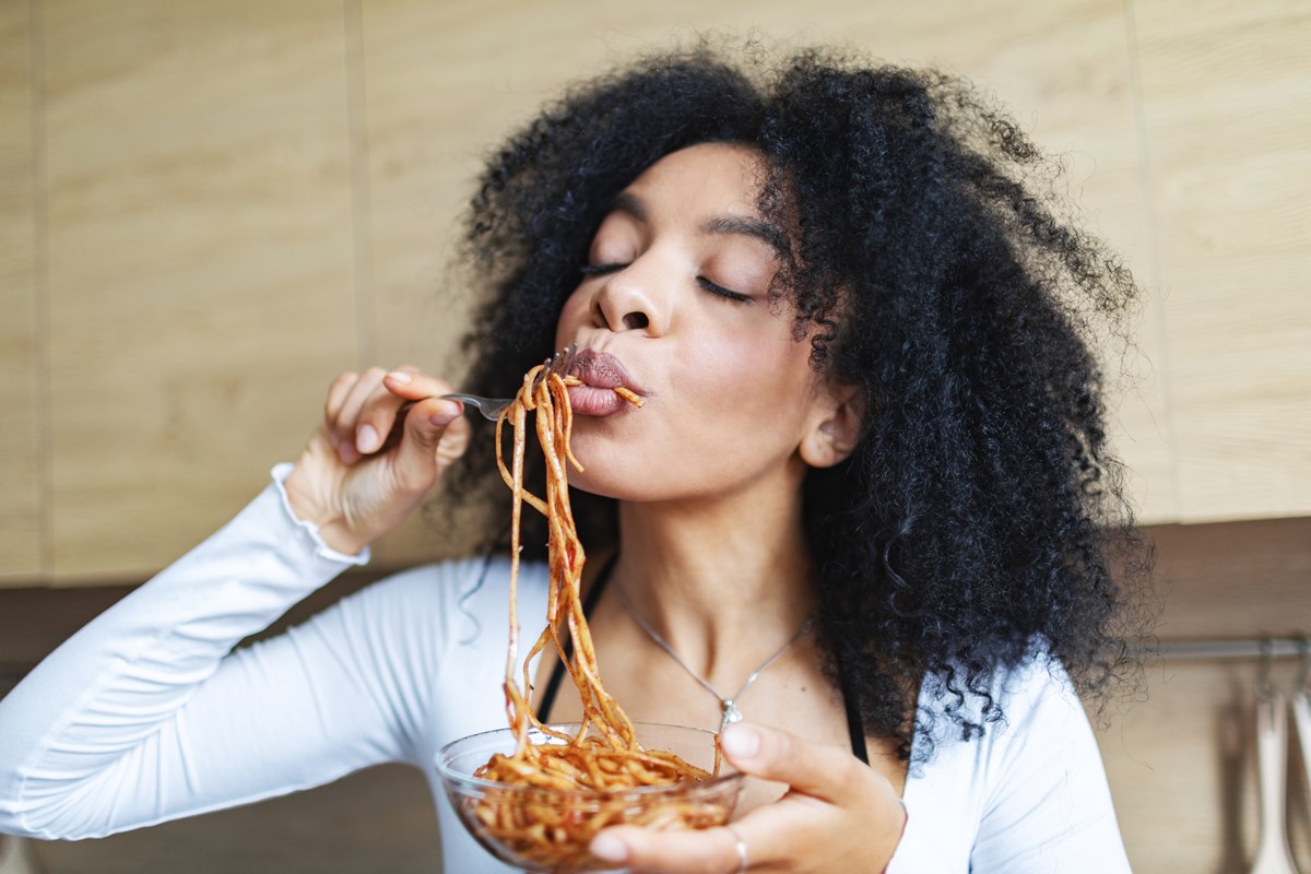 Foto colorida de mulher comendo espaguete - Metrópoles