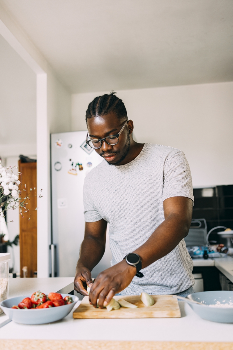 Homem negro preparando refeição com frutas na cozinha - Metrópoles