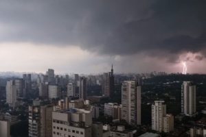 Enorme nuvem cinza cobre céu; um raio duplo é visto ao fundo da imagem - Metrópoles