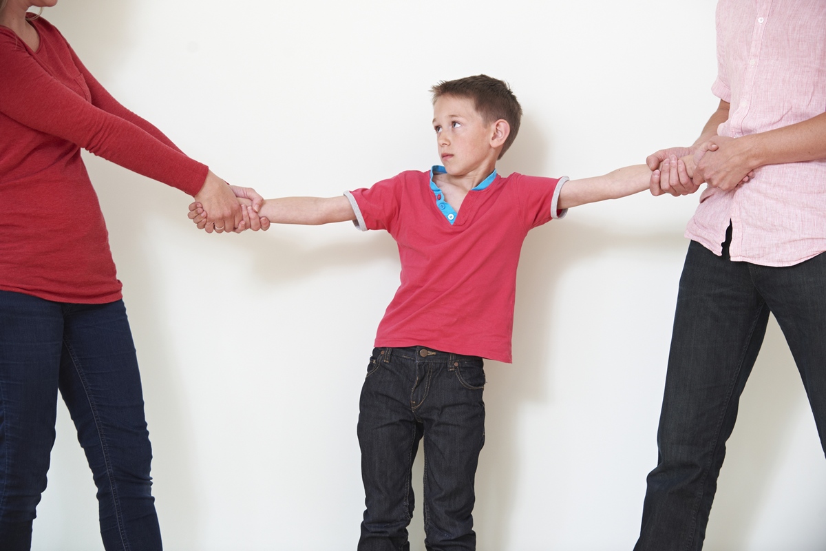 Pais segurando o filho pelo braço para representar a briga pela guarda no divórcio