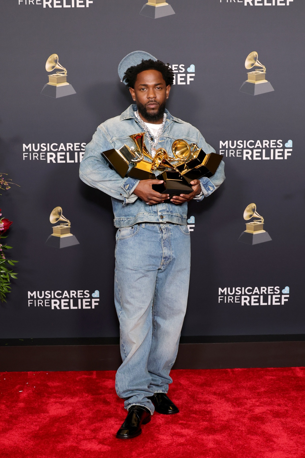 A imagem mostra o rapper Kendrick Lamar carregando seus troféus do grammy