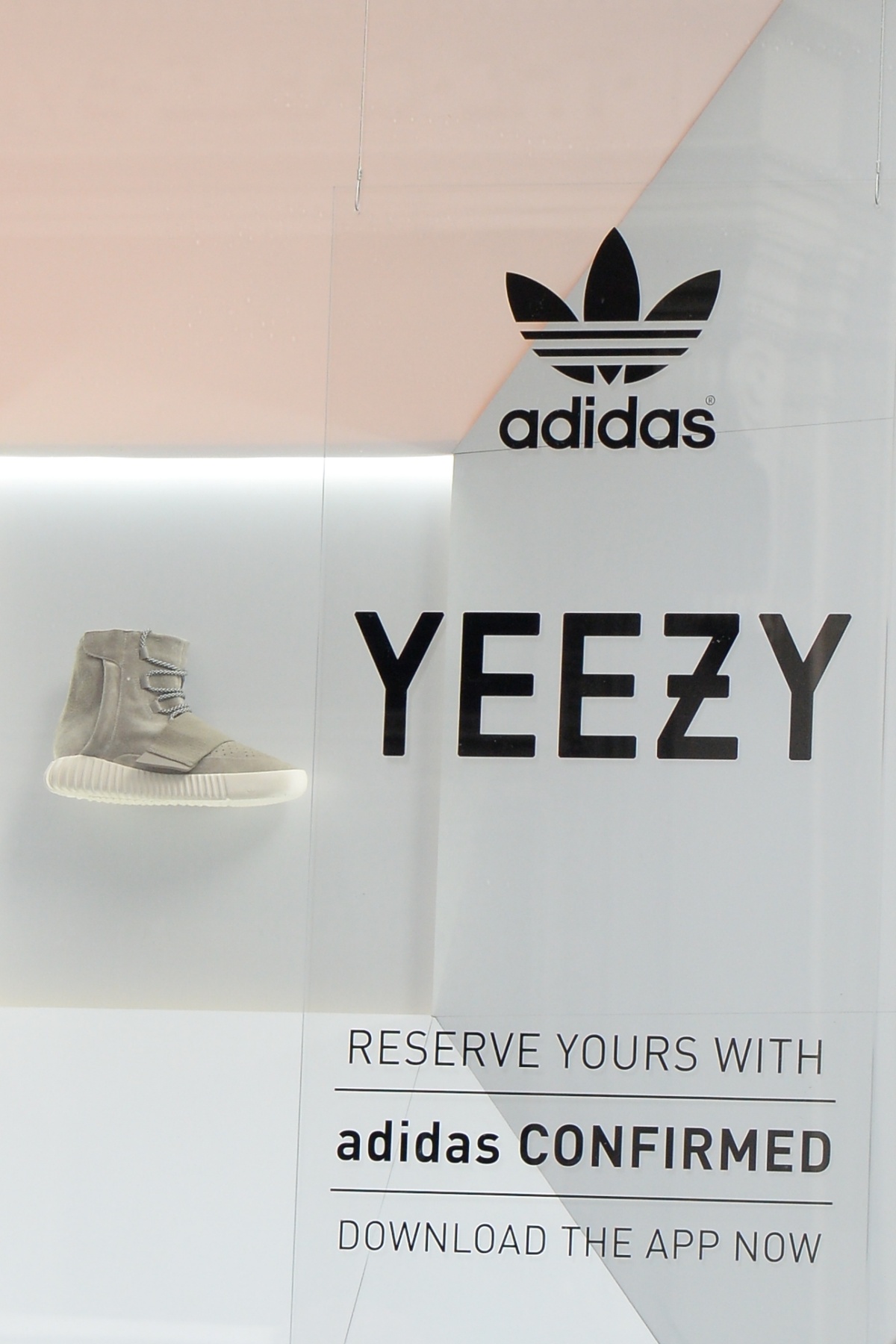 A imagem mostra uma vitrine da Adidas em colaboração com a marca Yeezy. Ao fundo, um tênis da colaboração está exposto