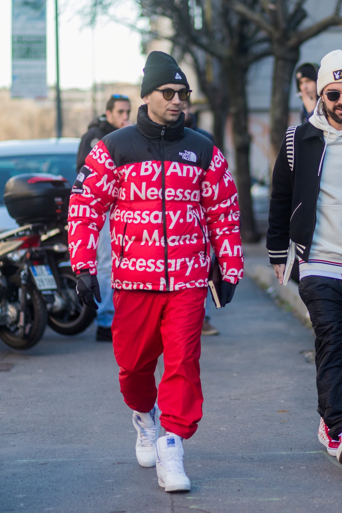 A imagem mostra um homem caminhando usando um casaco da The North Face com a Supreme