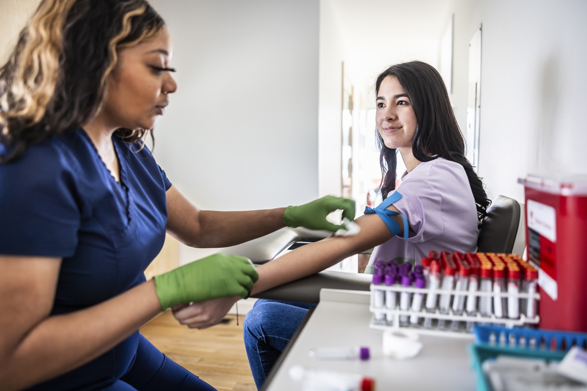 Jovem enfermeira fazendo exame de sangue em paciente mulher jovem - Metrópoles