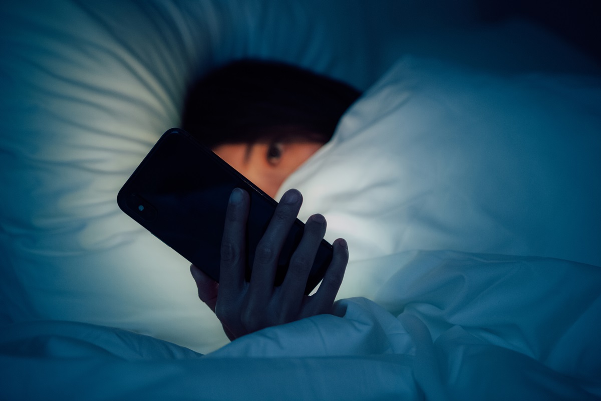 Foto de jovem utilizando celular antes de dormir - Metrópoles