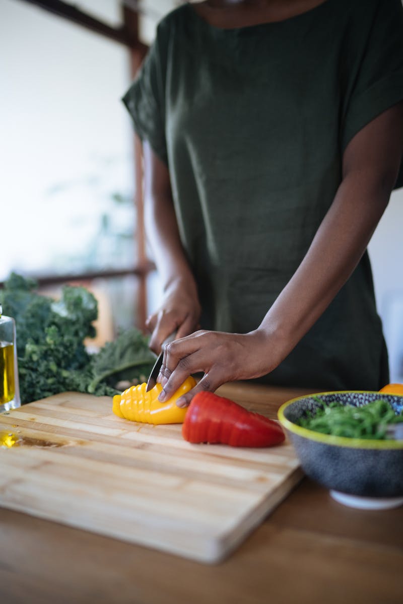 Mãos de mulher cortando pimentões em mesa de cozinha - Metrópoles