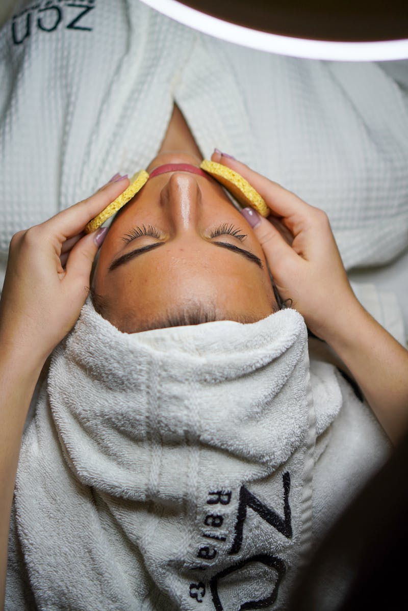 Mãos realizando massagem facial em rosto de jovem mulher - Metrópoles