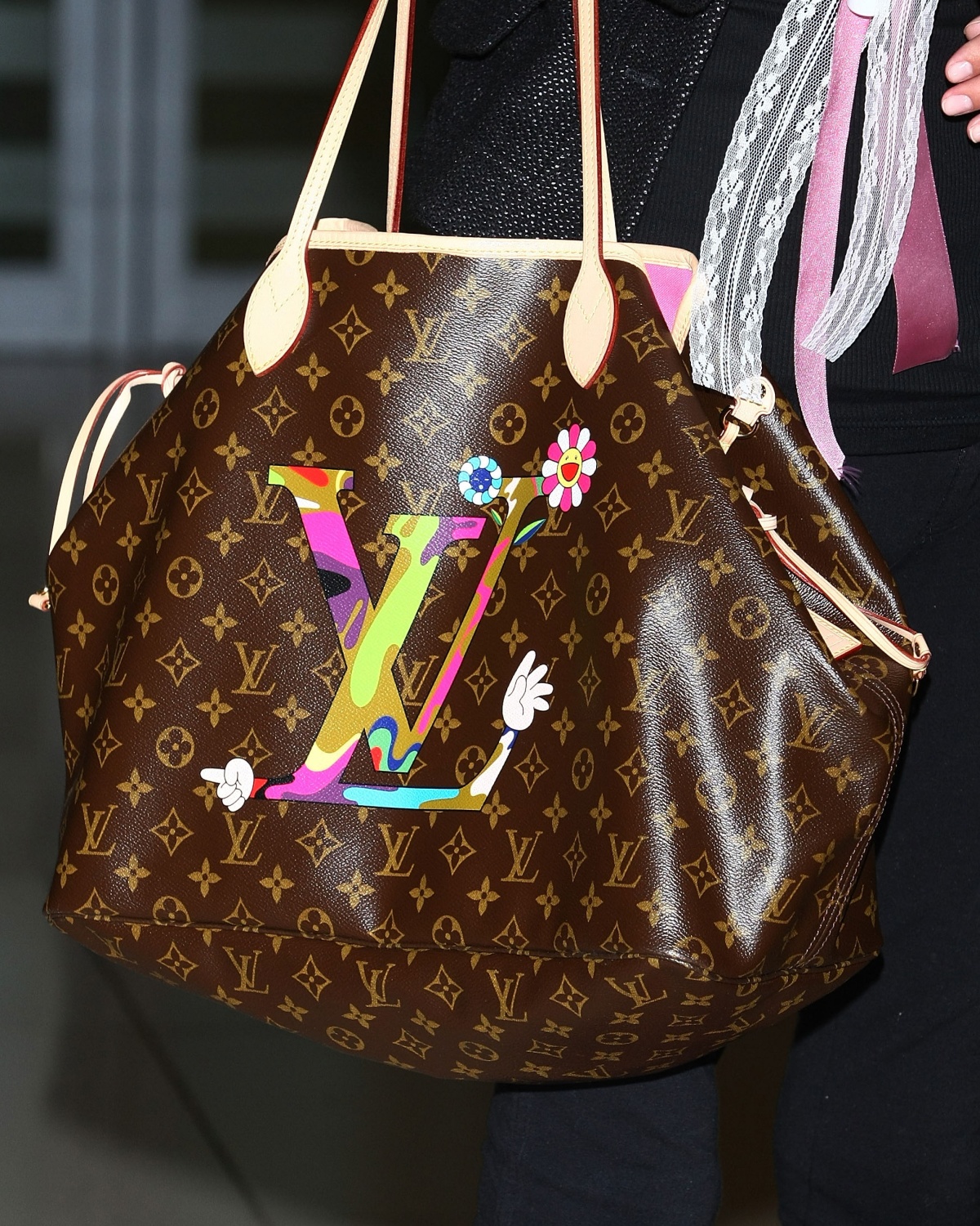 A imgem mostra uma bolsa da grife Louis Vuitton na cor marrom com um emblema LV colorido 