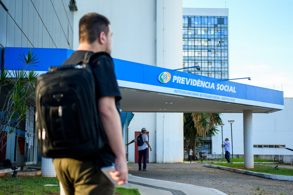 Fachada da Previdência Social e acesso digital aos serviços do INSS pelo aplicativo Meu INSS - Mertrópoles