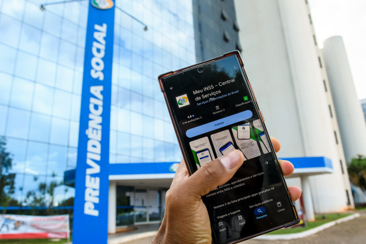 Fachada da Previdência Social e acesso digital aos serviços do INSS pelo aplicativo Meu INSS - Mertrópoles