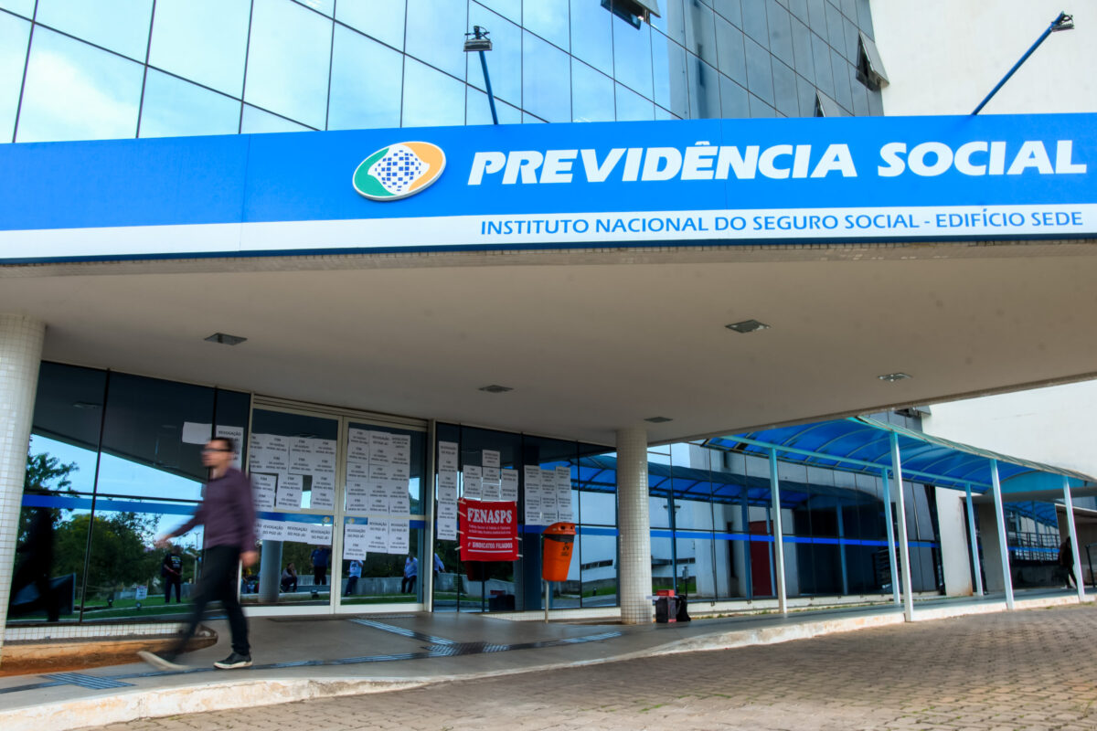 Fachada da Previdência Social e acesso digital aos serviços do INSS pelo aplicativo Meu INSS - Mertrópoles