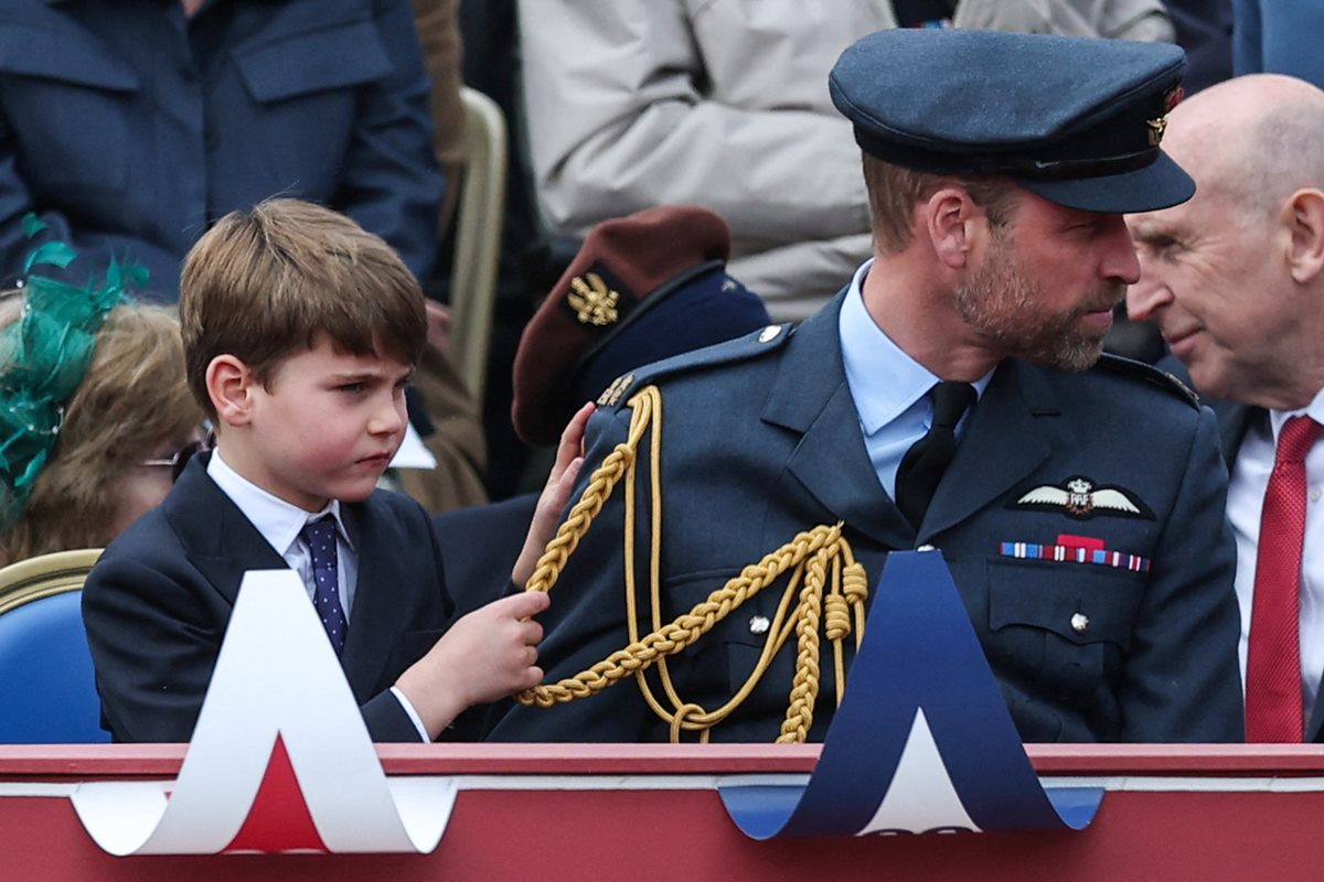 Foto colorida de menino puxando cordas de uniforme de homem, que conversa com um homem idoso ao lado - Metrópoles