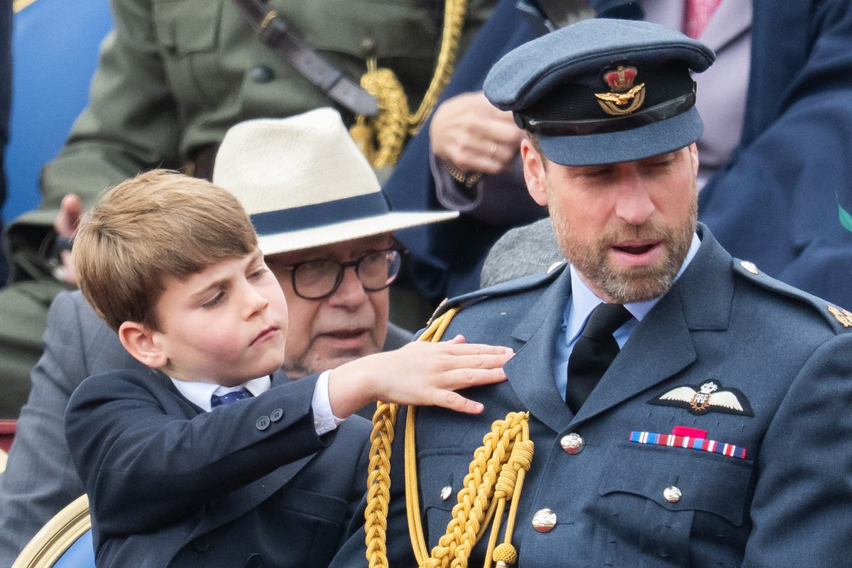 Foto colorida de menino limpando uniforme militar de homem ao lado - Metrópoles