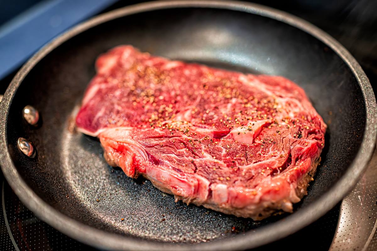 Foto colorida de carne em frigideira - Metrópoles