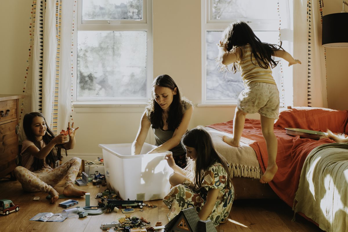 Foto colorida de mulher e três crianças crianças brincando em um quarto - Metrópoles