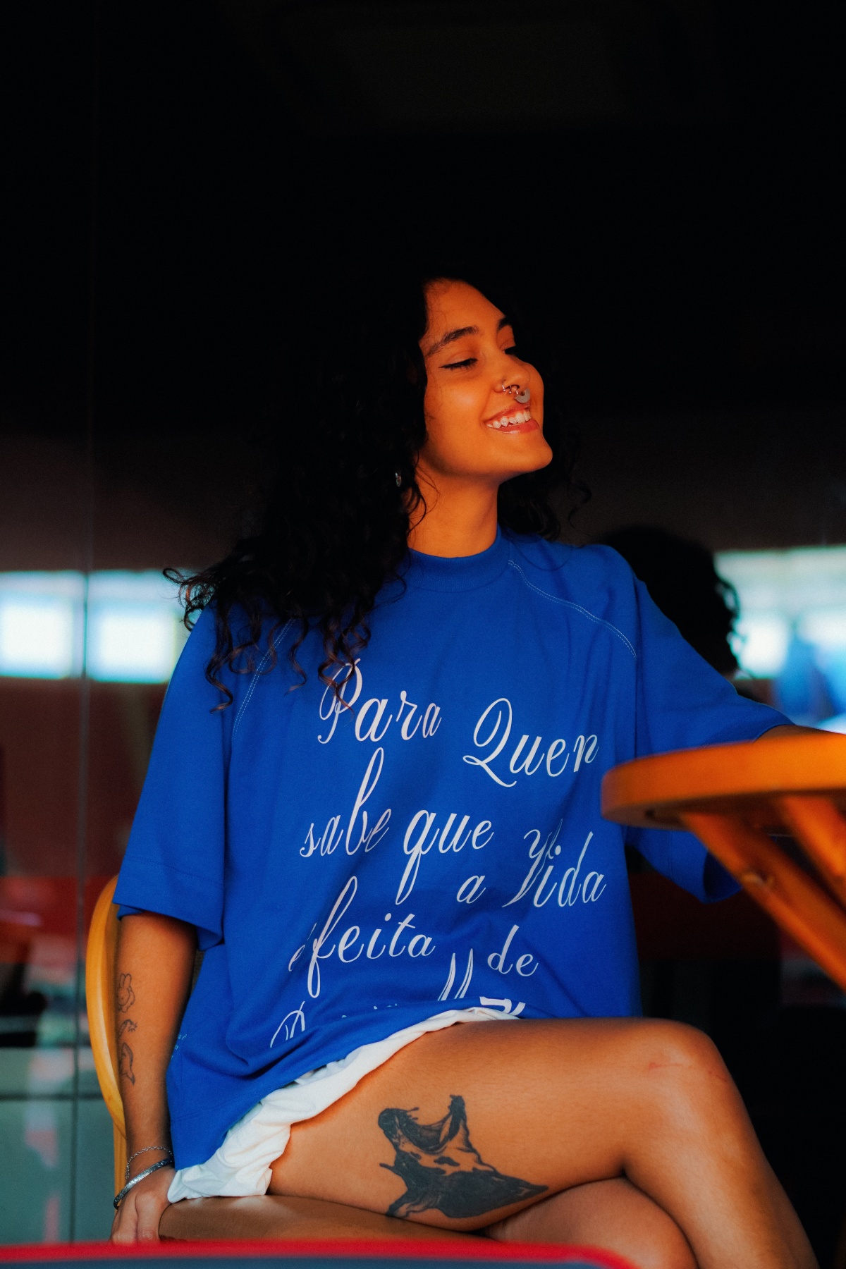 A imagvem mostra uma jovem sorridente vestindo uma camiseta azul