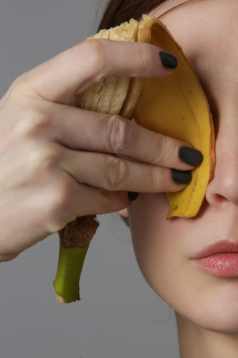 Foto colorida de mulher passando casca de banana no rosto - Metrópoles