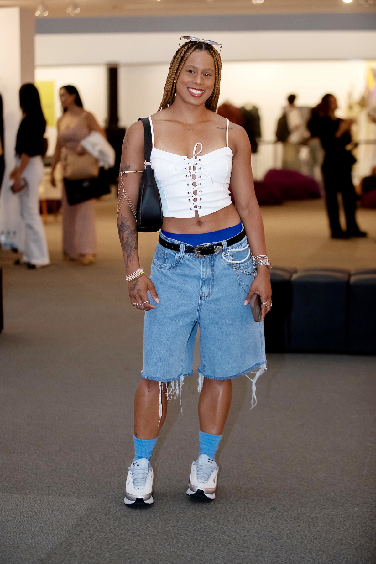 A imagem mostra uma jovem de cropped branco e shorts jeans 