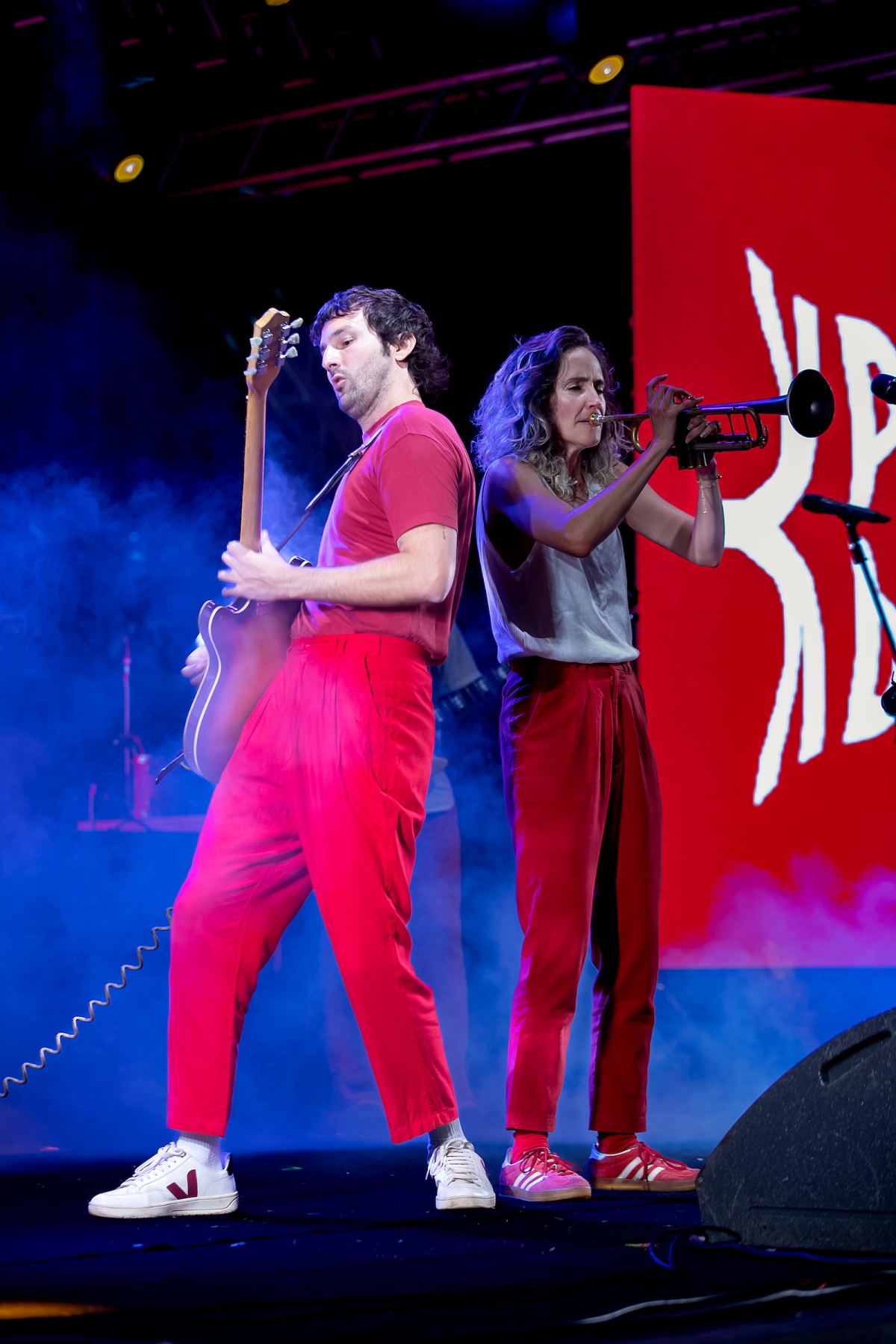 A imagem mostra dois artistas se apresentando no palco do festival