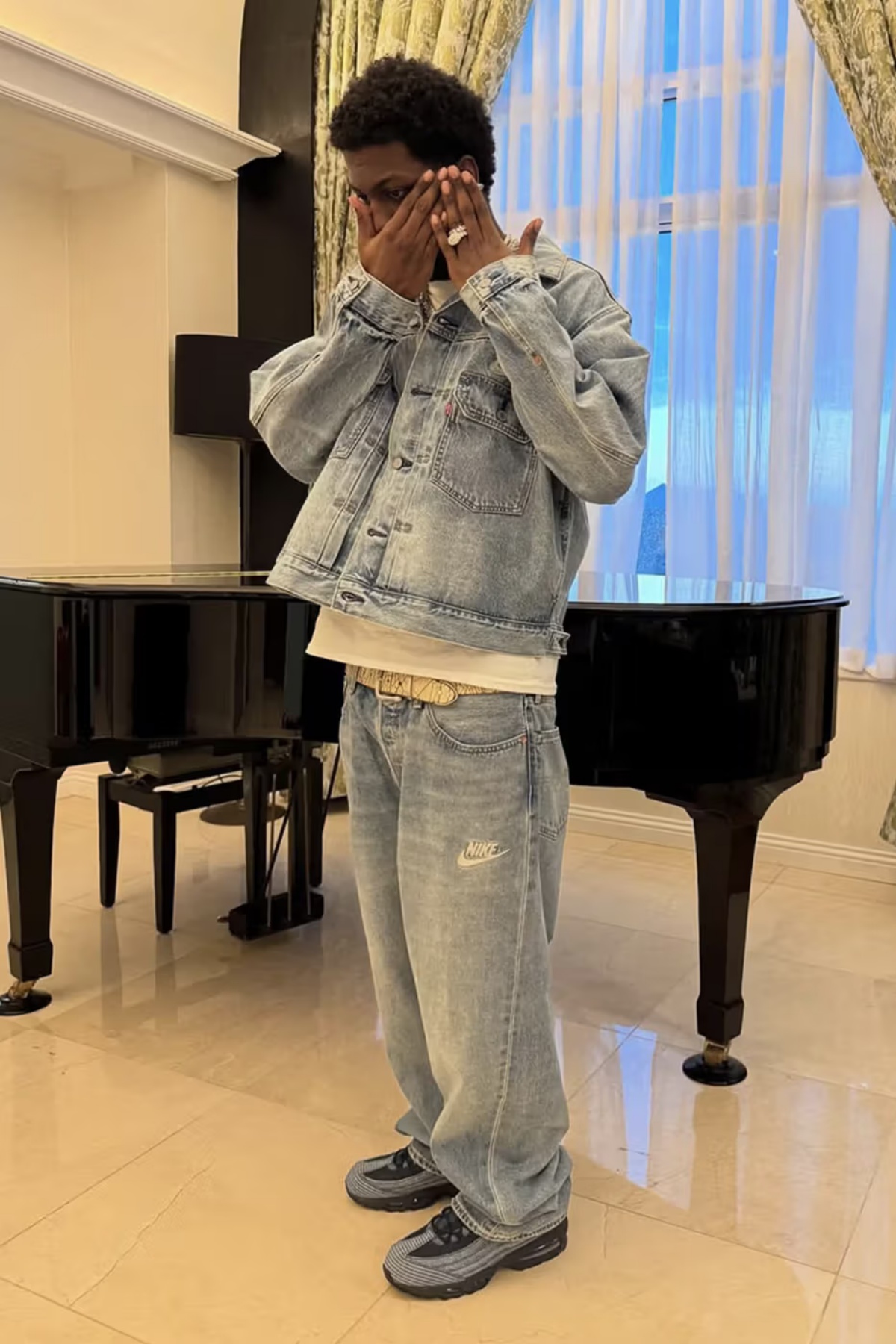 A imagem mostra um homem vestindo um conjunto de jaqueta e calça jeans