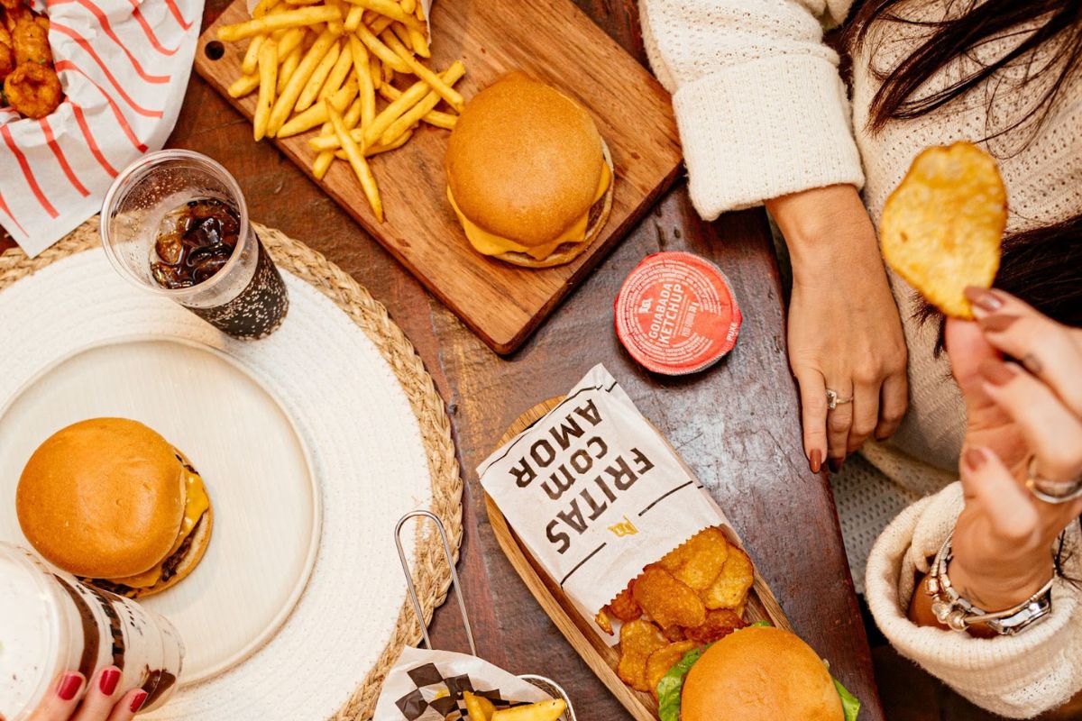 foto colorida de hamburguer e batatas em uma mesa