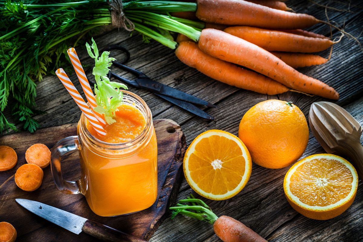 foto colorida de mesa com suco laranja e vários ingredientes 