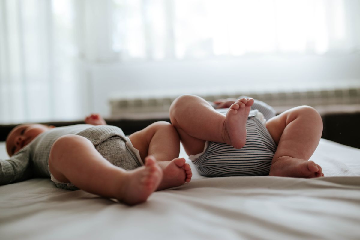 foto colorida dos pezinhos de dois bebes gêmeos na cama