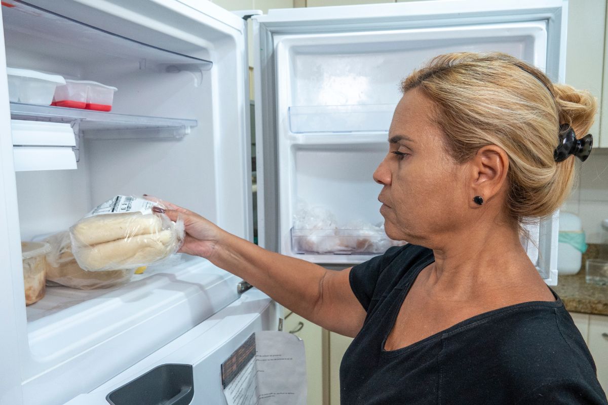 color photo of blonde woman putting bread in freezer