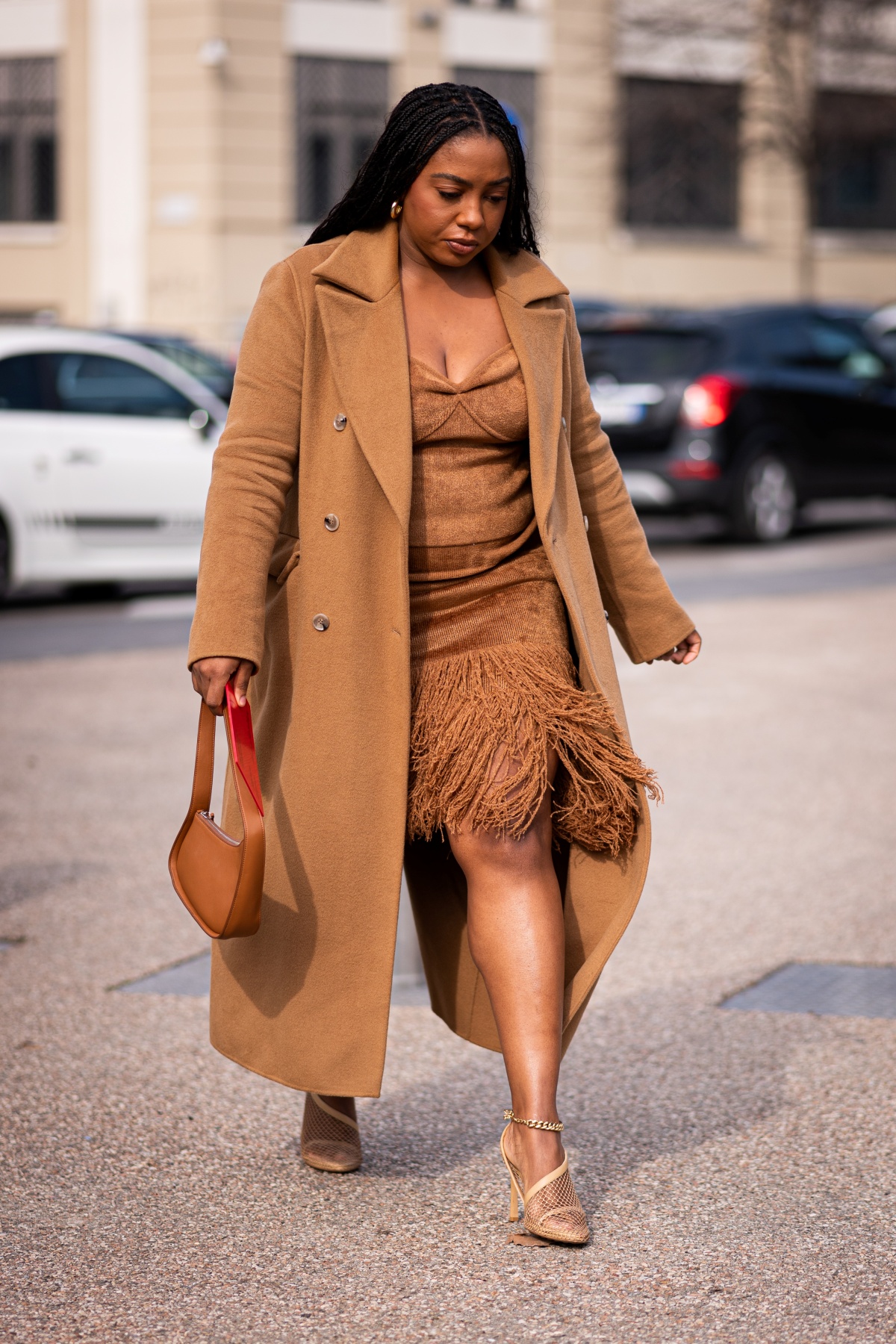 A imagem mostra uma mulher caminhando na rua com roupas em tons terrosos
